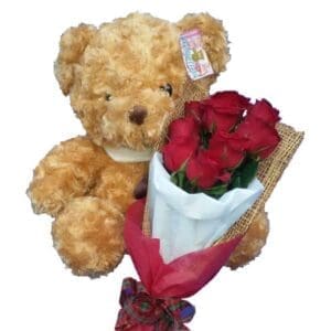 Traditional brown Teddy Bear together with a bunch of Red Rose, close up