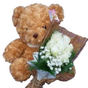 Traditional brown Teddy Bear together with a bunch of White Rose, close up